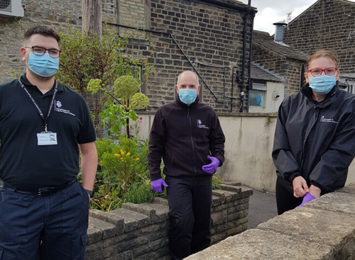 Three GLAA officers outside a terrace house wearing PPE masks and gloves